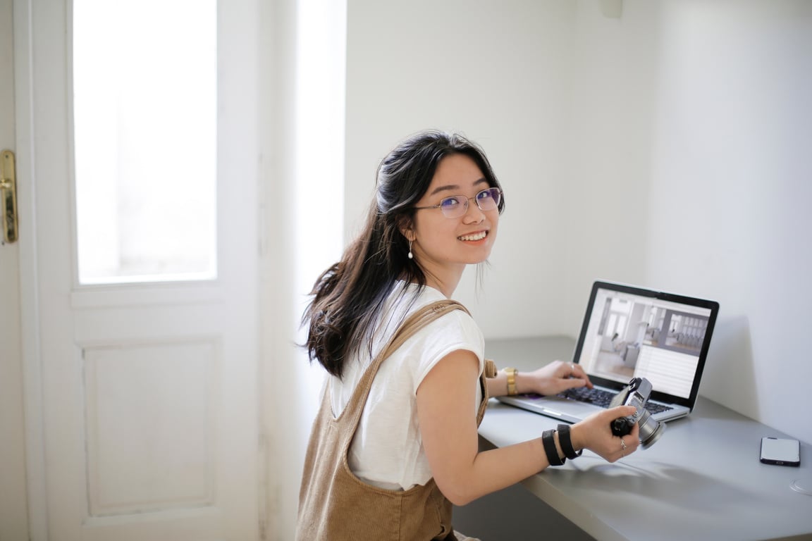 Delighted Asian photographer using laptop